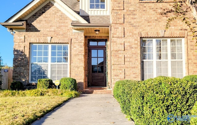 entrance to property featuring brick siding, board and batten siding, and a shingled roof