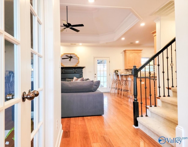 living room featuring recessed lighting, a ceiling fan, light wood-style floors, a tray ceiling, and crown molding