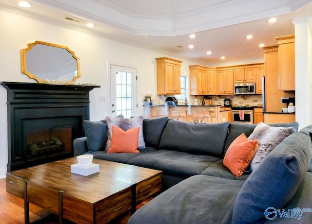 living room featuring ornamental molding, a fireplace, visible vents, and recessed lighting