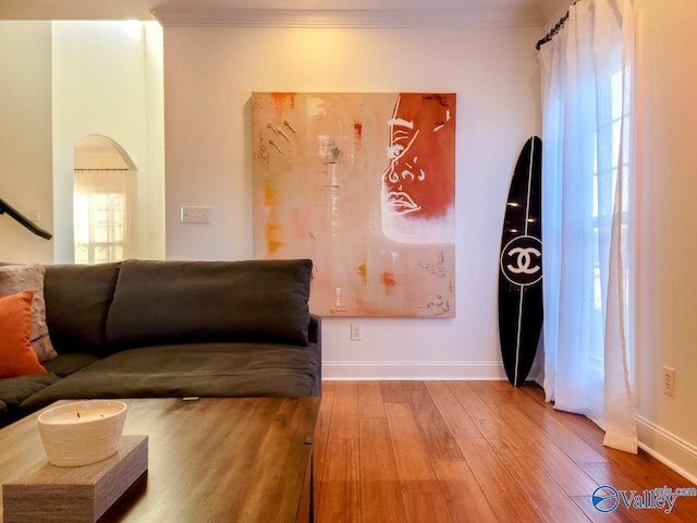 living room featuring ornamental molding, arched walkways, baseboards, and hardwood / wood-style floors