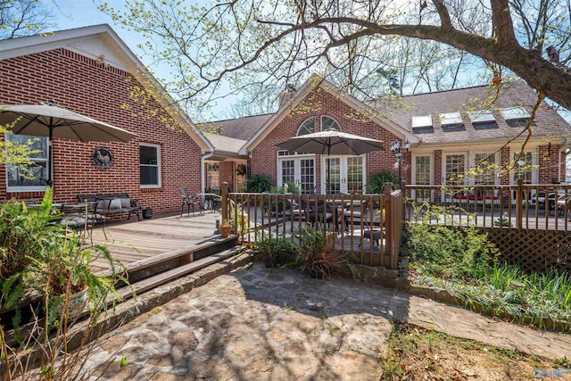back of property with a wooden deck, brick siding, and a shingled roof