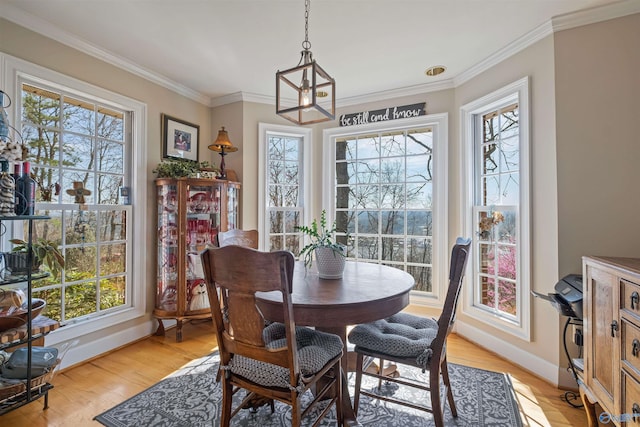 dining room with a notable chandelier, light wood-type flooring, crown molding, and baseboards