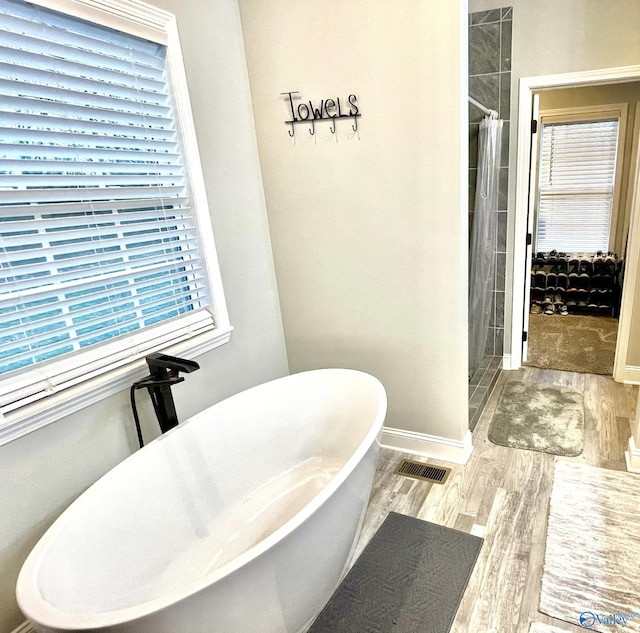 bathroom with hardwood / wood-style flooring and shower with separate bathtub