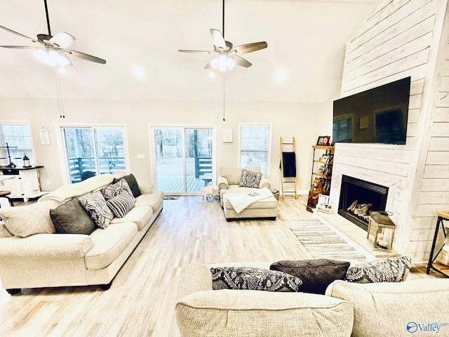 living room featuring high vaulted ceiling, a healthy amount of sunlight, ceiling fan, and light hardwood / wood-style flooring