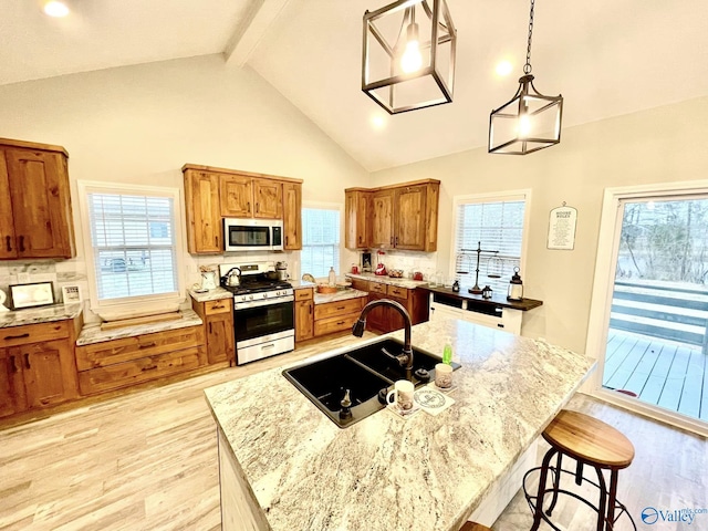 kitchen featuring pendant lighting, appliances with stainless steel finishes, sink, and a kitchen island with sink