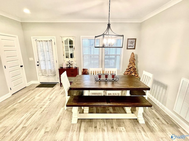 dining area with an inviting chandelier, crown molding, and light hardwood / wood-style flooring