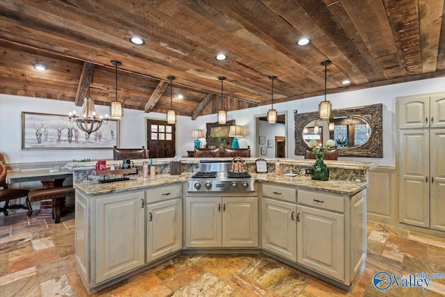 kitchen with light stone counters, stone tile floors, stainless steel gas stovetop, a kitchen island with sink, and wooden ceiling