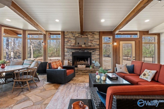 living area featuring recessed lighting, stone tile floors, beam ceiling, and a stone fireplace