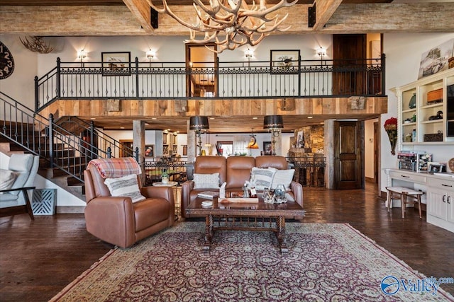 living room with a towering ceiling, stairs, wood finished floors, and beamed ceiling