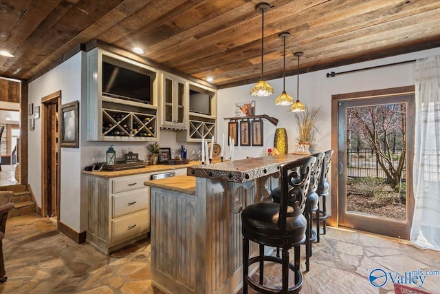 bar featuring wooden ceiling, stone tile floors, indoor wet bar, and decorative light fixtures