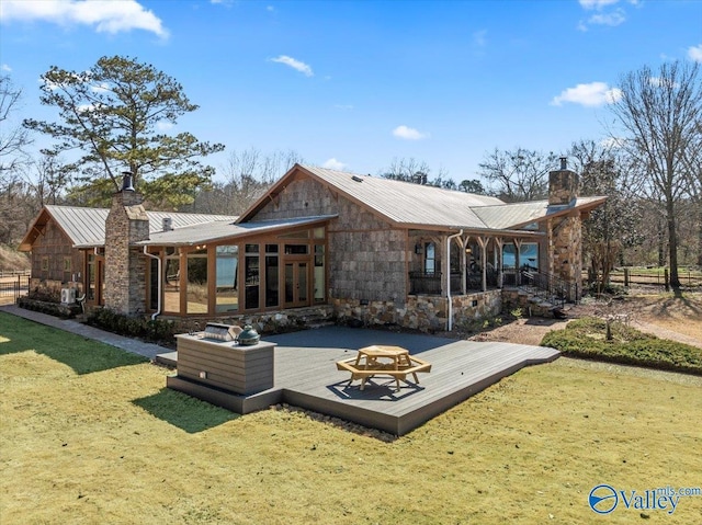 rear view of property featuring metal roof, a chimney, a wooden deck, and a lawn