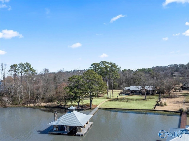 view of dock with a water view, a lawn, and a wooded view