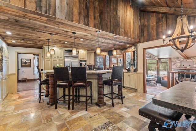 kitchen with appliances with stainless steel finishes, stone tile flooring, a high ceiling, and a kitchen bar