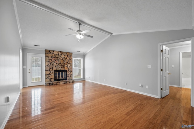 unfurnished living room with wood-type flooring, lofted ceiling with beams, a stone fireplace, and ceiling fan