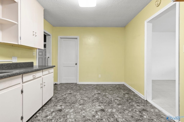 kitchen featuring white cabinets and a textured ceiling