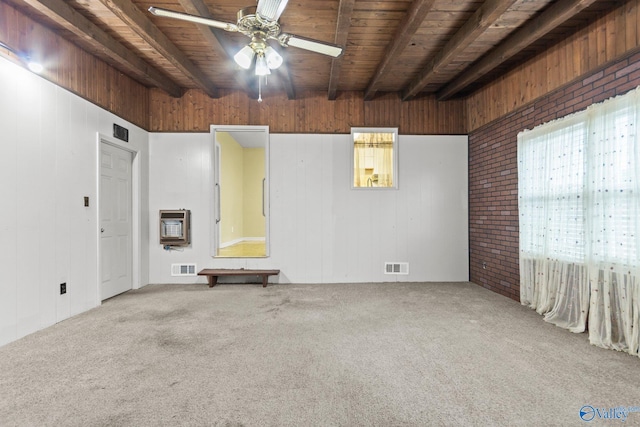 spare room featuring carpet flooring, beam ceiling, and heating unit