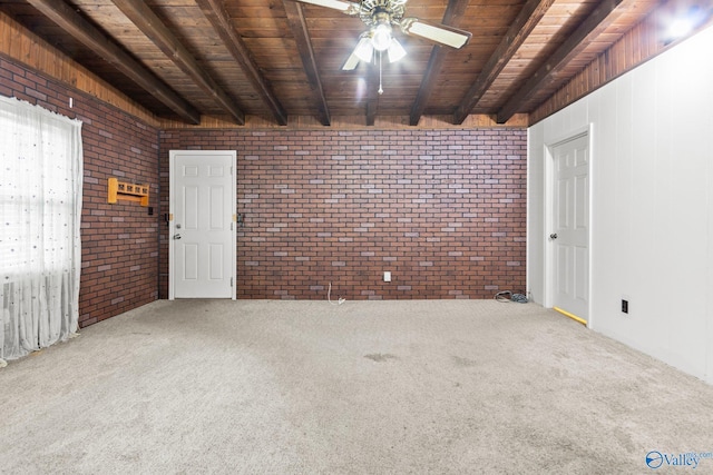 carpeted spare room featuring ceiling fan, beam ceiling, wooden ceiling, and brick wall