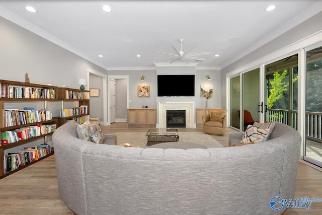 living room featuring ceiling fan, crown molding, and light hardwood / wood-style floors