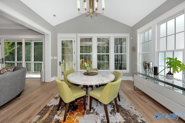 dining room with light wood-type flooring, vaulted ceiling, and a chandelier