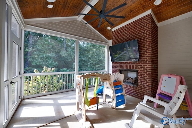 sunroom / solarium with wood ceiling, vaulted ceiling, ceiling fan, and a fireplace