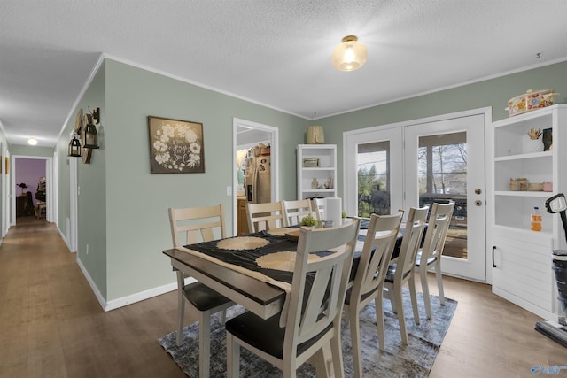 dining room featuring ornamental molding, a textured ceiling, baseboards, and wood finished floors