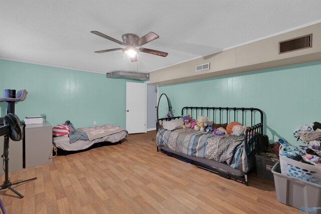 bedroom with a ceiling fan, visible vents, crown molding, and wood finished floors