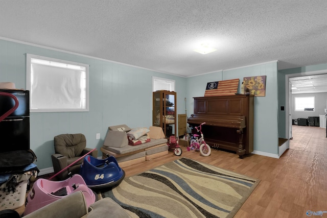 interior space with a textured ceiling, ornamental molding, and wood finished floors