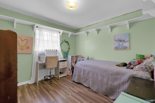 bedroom with a textured ceiling, wood finished floors, and baseboards