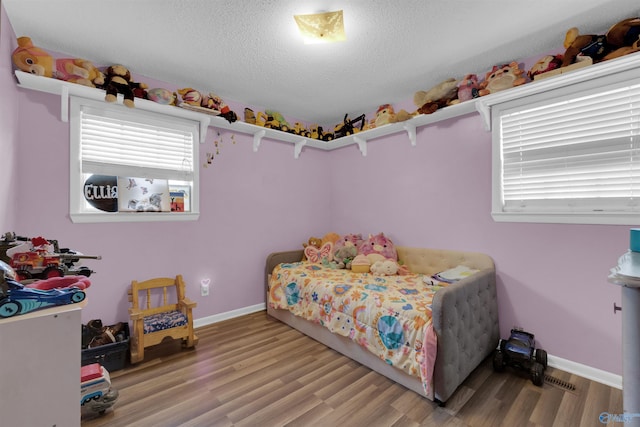 bedroom with a textured ceiling, baseboards, and wood finished floors