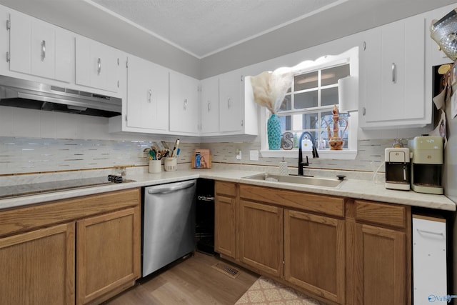 kitchen with black electric stovetop, light countertops, stainless steel dishwasher, a sink, and under cabinet range hood