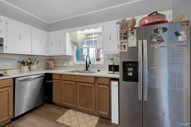 kitchen featuring light countertops, decorative backsplash, appliances with stainless steel finishes, a sink, and wood finished floors