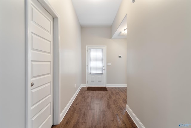 doorway featuring baseboards and dark wood-style flooring
