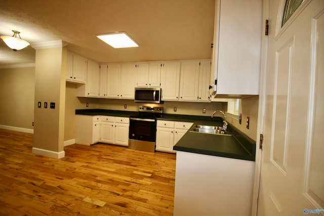 kitchen featuring appliances with stainless steel finishes, white cabinets, sink, crown molding, and light wood-type flooring