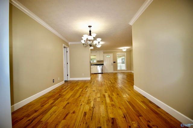 unfurnished living room with a chandelier, light wood-type flooring, and ornamental molding