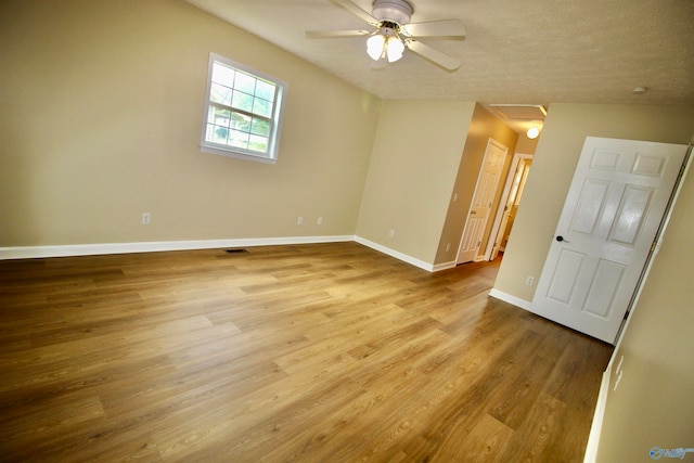 empty room featuring light hardwood / wood-style floors, a textured ceiling, ceiling fan, and lofted ceiling