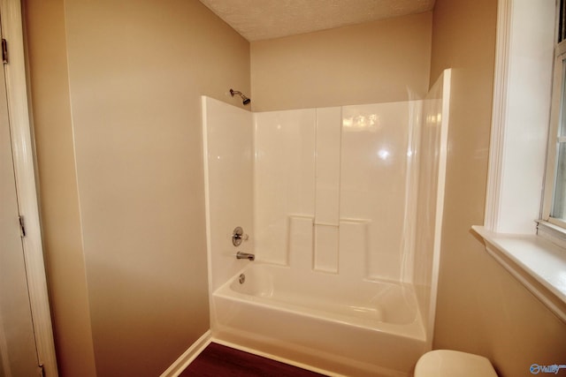 bathroom featuring bathing tub / shower combination, toilet, a textured ceiling, and hardwood / wood-style floors