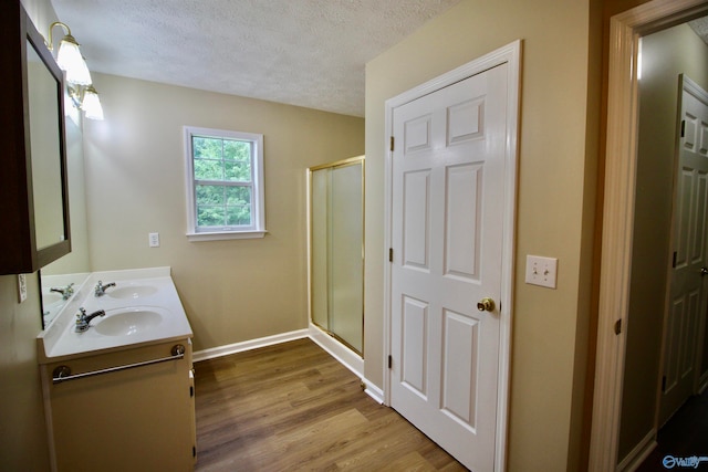 bathroom with walk in shower, a textured ceiling, hardwood / wood-style floors, and dual bowl vanity