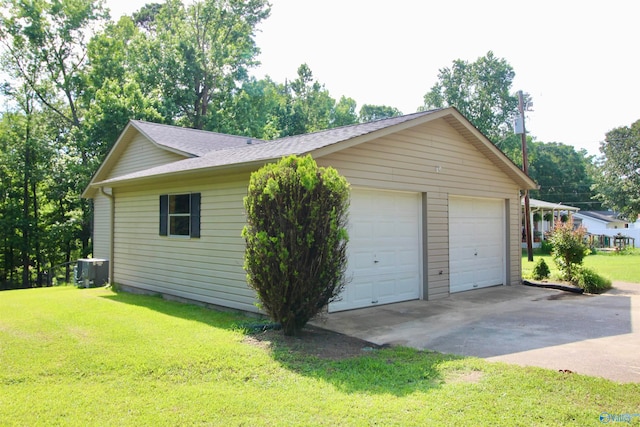 garage with central AC unit and a lawn