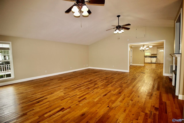 empty room featuring vaulted ceiling, ceiling fan with notable chandelier, and light wood-type flooring