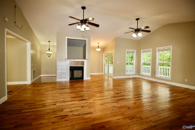 unfurnished living room featuring a fireplace, ceiling fan with notable chandelier, light wood-type flooring, and vaulted ceiling