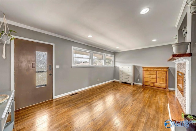 unfurnished living room with ornamental molding, wood finished floors, visible vents, and baseboards