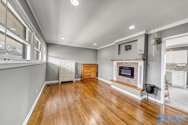 unfurnished living room with recessed lighting, baseboards, wood finished floors, and ornamental molding