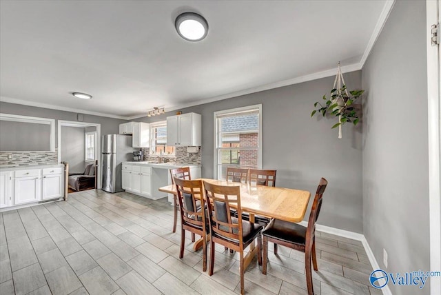 dining room featuring light wood-style floors, baseboards, and crown molding