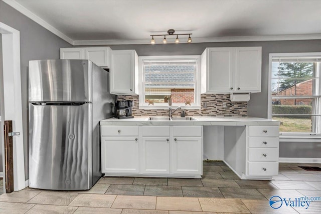 kitchen with freestanding refrigerator, white cabinetry, a sink, and decorative backsplash