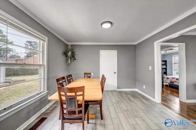 dining area featuring crown molding, baseboards, a wealth of natural light, and light wood-style floors