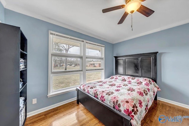 bedroom with ornamental molding, wood finished floors, and baseboards