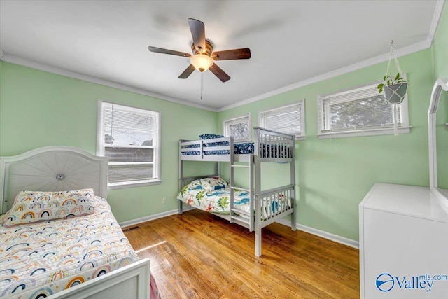 bedroom with crown molding, baseboards, ceiling fan, and wood finished floors