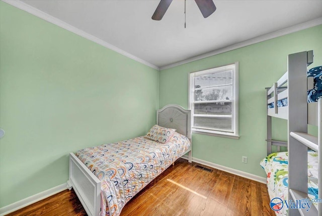 bedroom with baseboards, wood finished floors, and crown molding