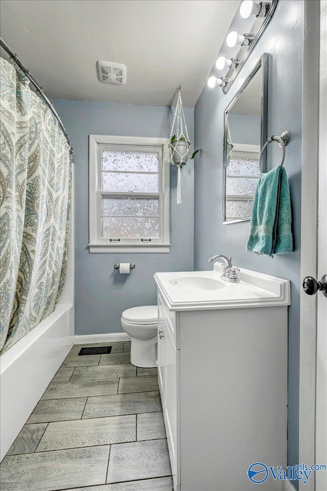 bathroom featuring a wealth of natural light, wood finish floors, vanity, and toilet