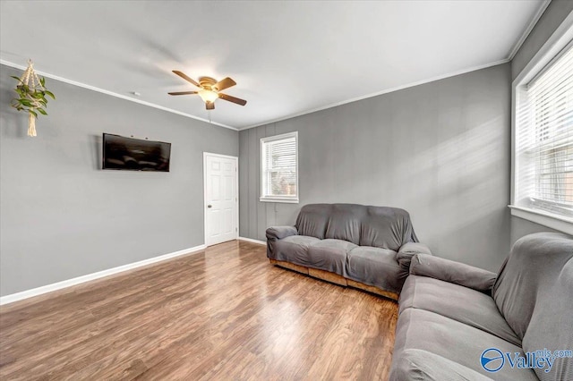 living room with ornamental molding, a healthy amount of sunlight, baseboards, and wood finished floors